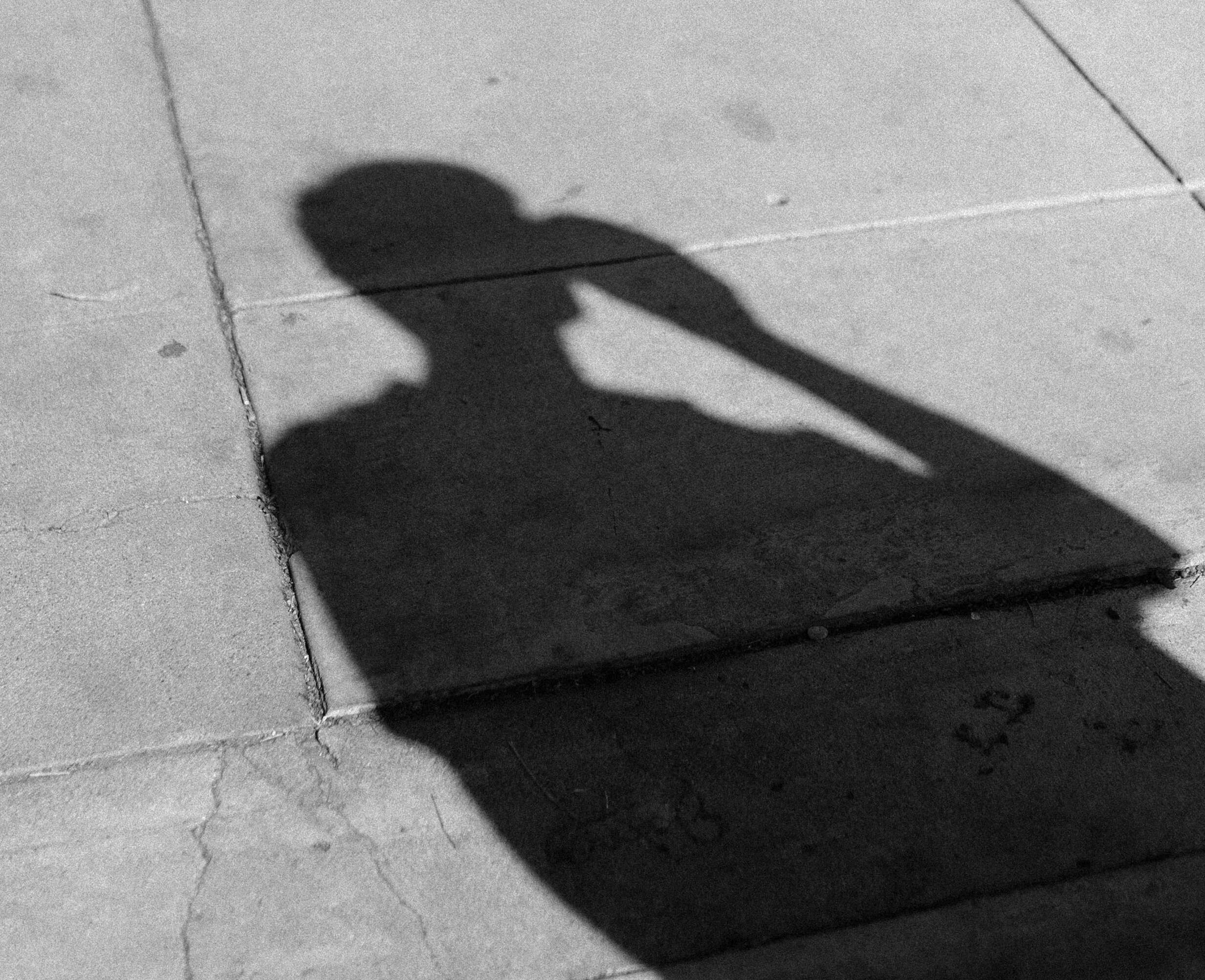 shadow of a man walking on the concrete in downtown phoenix, arizona