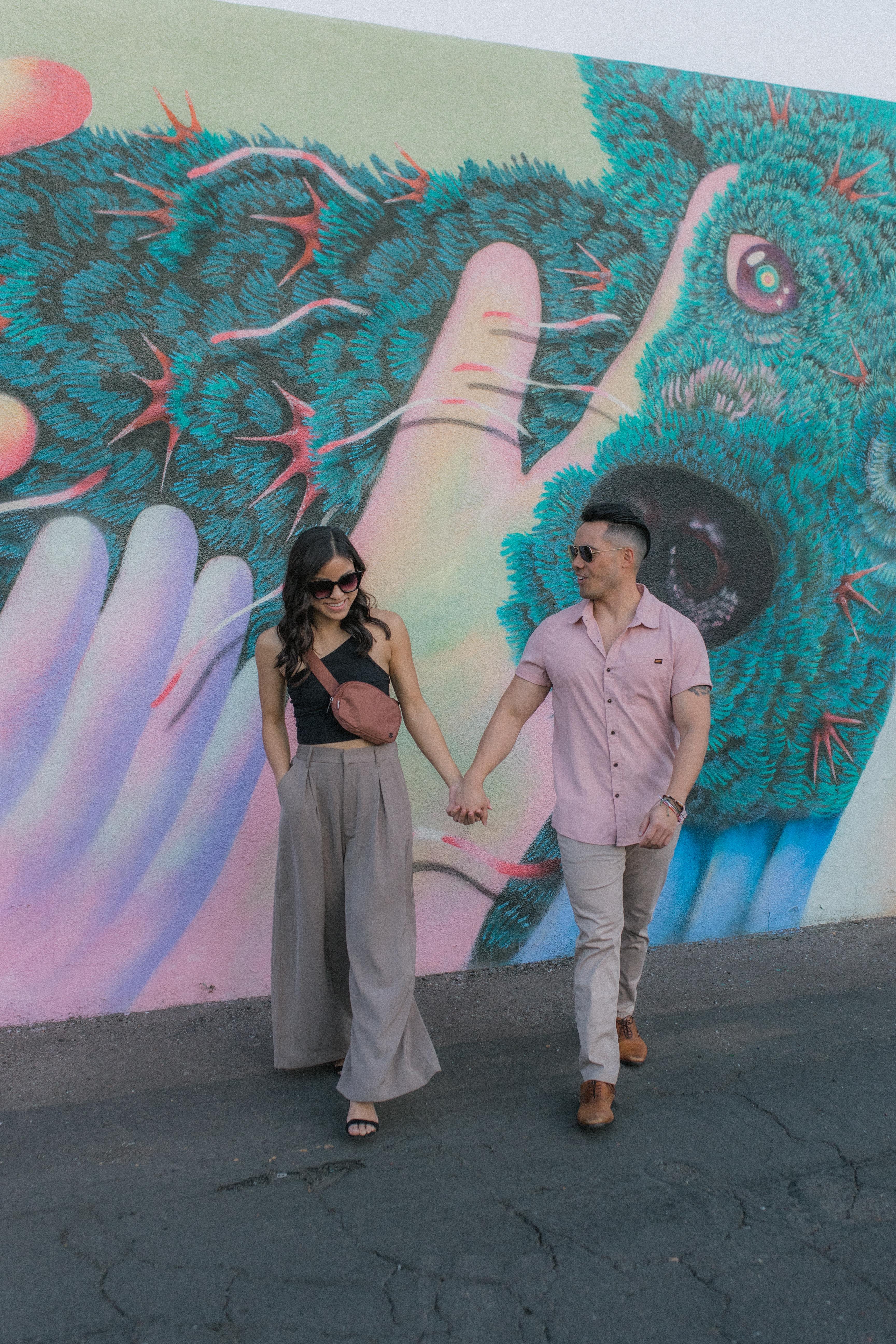 Image of two individuals in front of a colorful mural