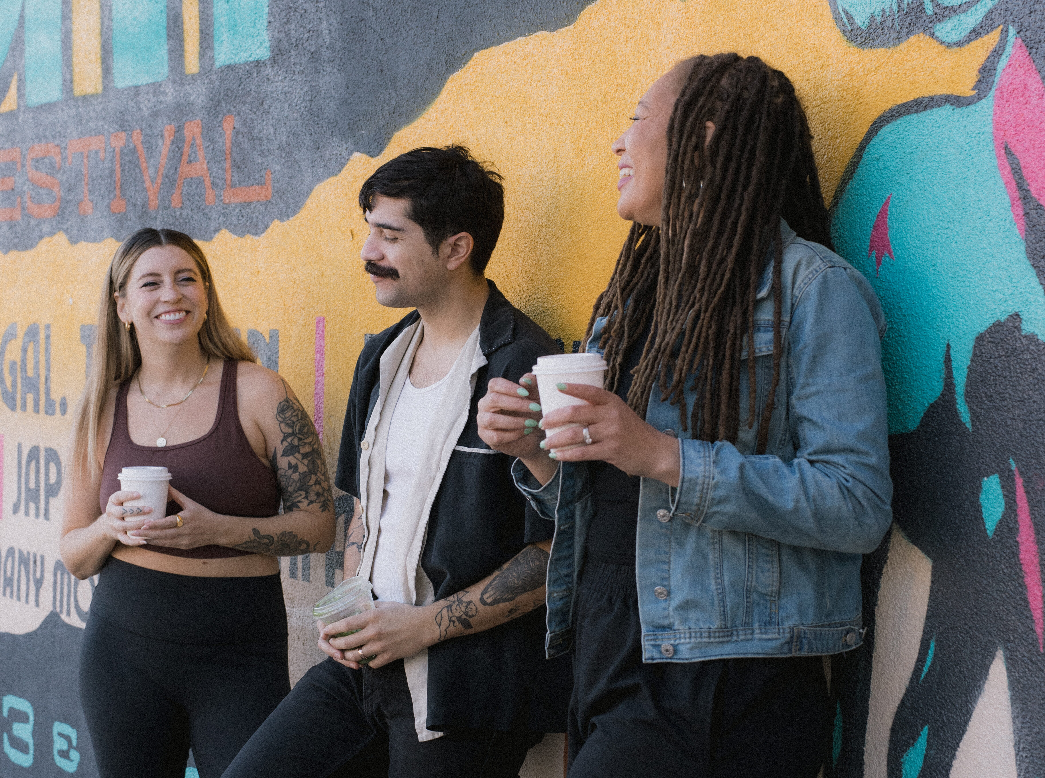 Three friends smiling and chatting over coffee on Roosevelt Row in downtown Phoenix.