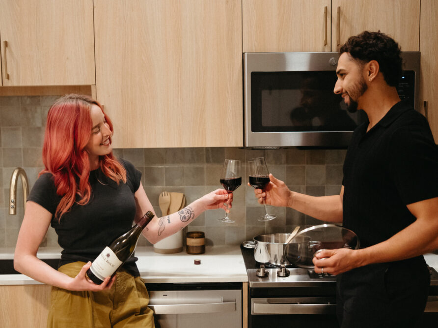Two roommates clinking wine glass in their two-bedroom apartment